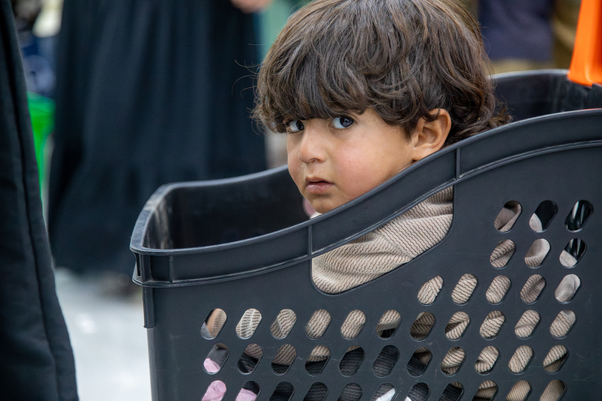 A small child peeking out from inside a shopping basket during HDF's pre-Eid shopping outing in Al Marfaq, Jordan.