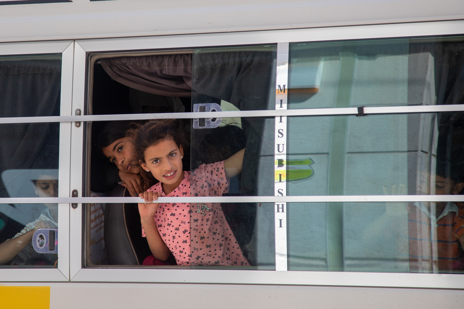 Children looking out from a bus window on their way to HDF's pre-Eid shopping outing in Al Marfaq, Jordan.