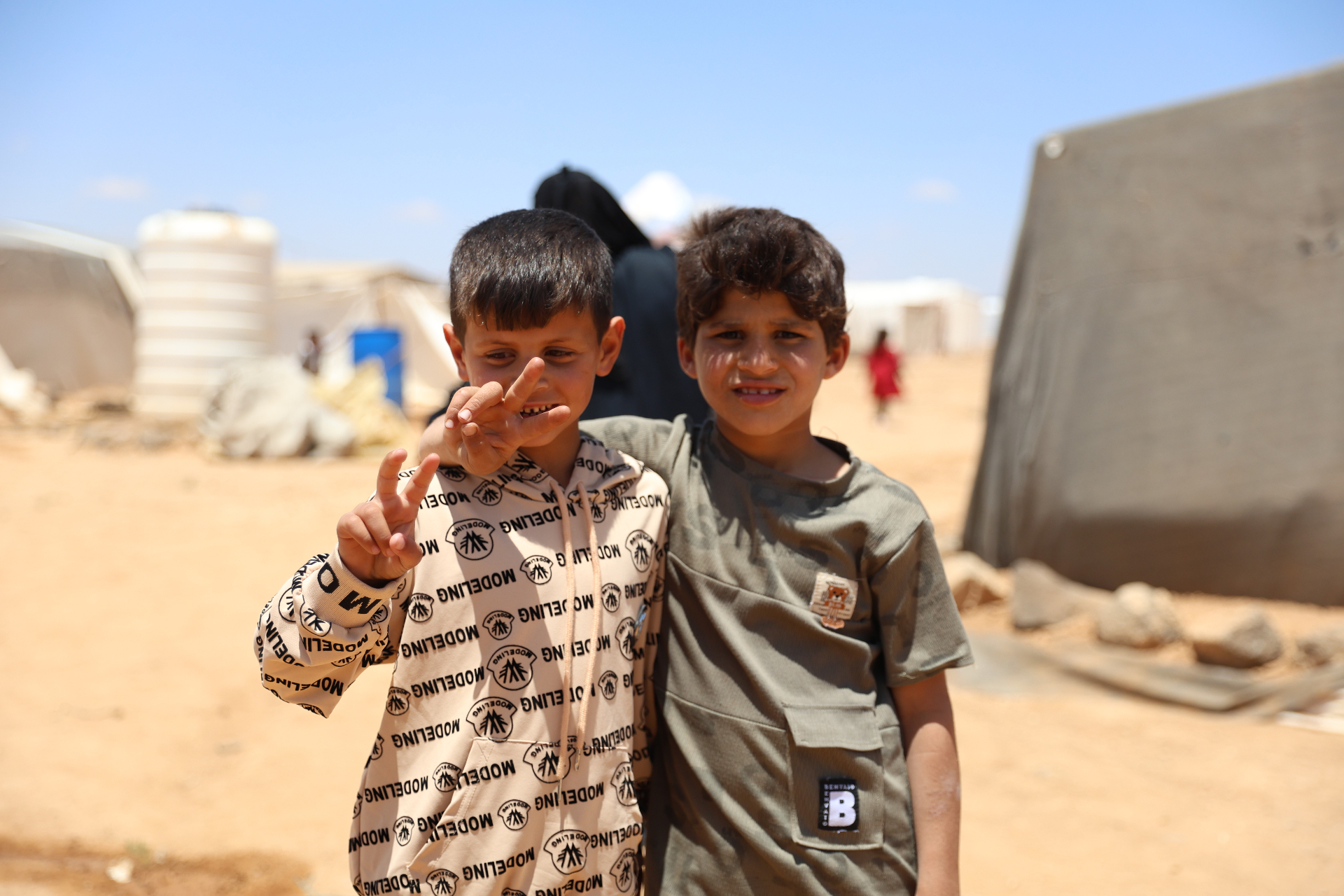 Two boys from HDF beneficiary families in Al Marfaq, Jordan, standing together outdoors.