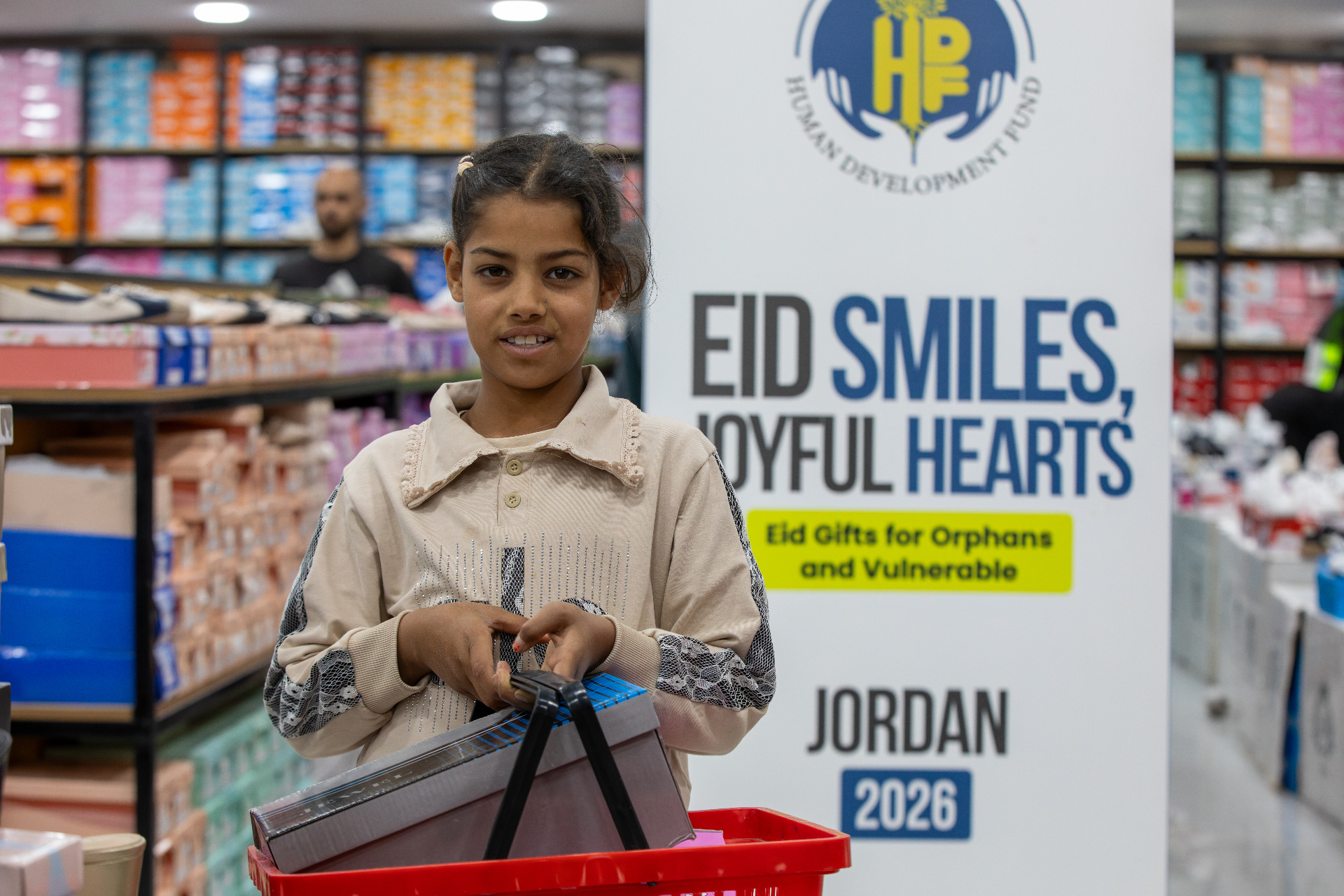A girl holding her Eid items after shopping through HDF's beneficiary outing in Al Marfaq, Jordan.