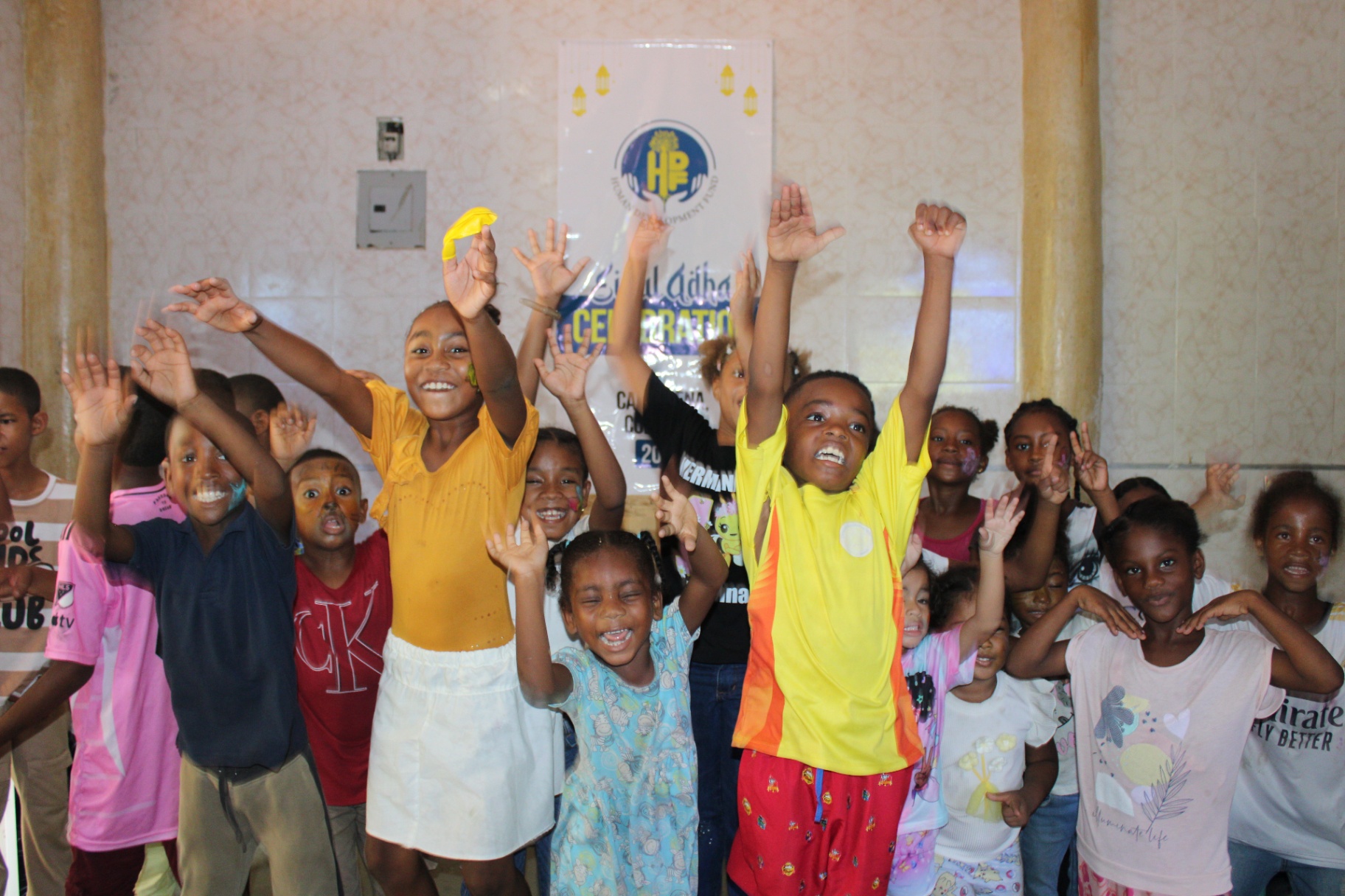 A group of children cheering with hands raised at HDF's Eid celebration in Cartagena, Colombia.
