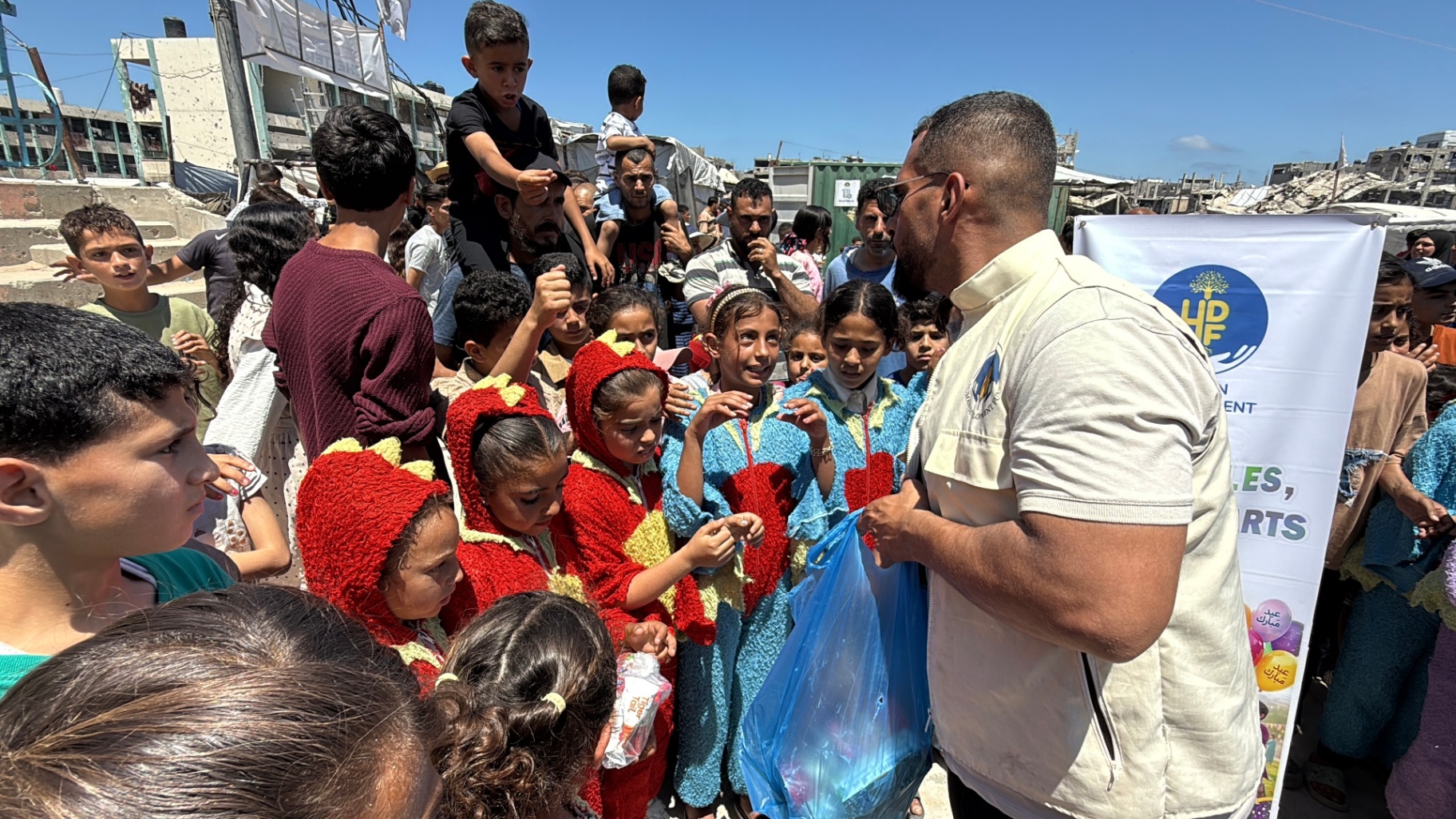 Costumed children gathered to receive Eid gift bags from an HDF team member in Gaza.