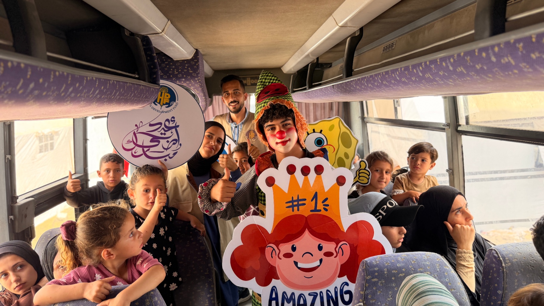 Children, volunteers, and entertainment staff inside HDF's Eid outing bus in Gaza.