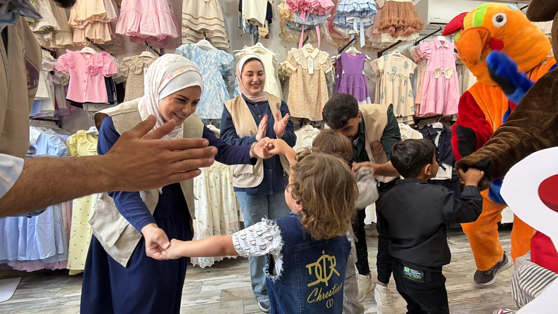 HDF volunteers and children celebrating inside a clothing shop during the pre-Eid shopping experience in Gaza.