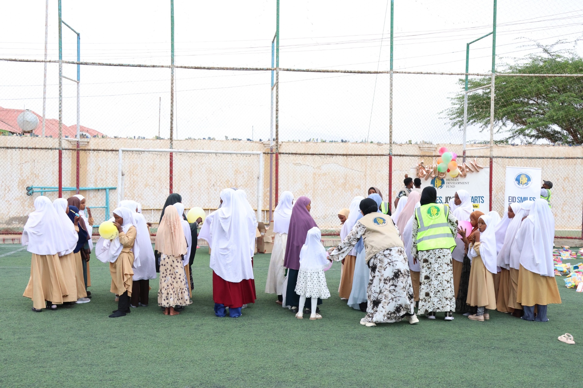 Girls in white hijabs gathered in a circle with HDF volunteers at the Eid Smiles, Joyful Hearts celebration in Hargeisa, Somalia.