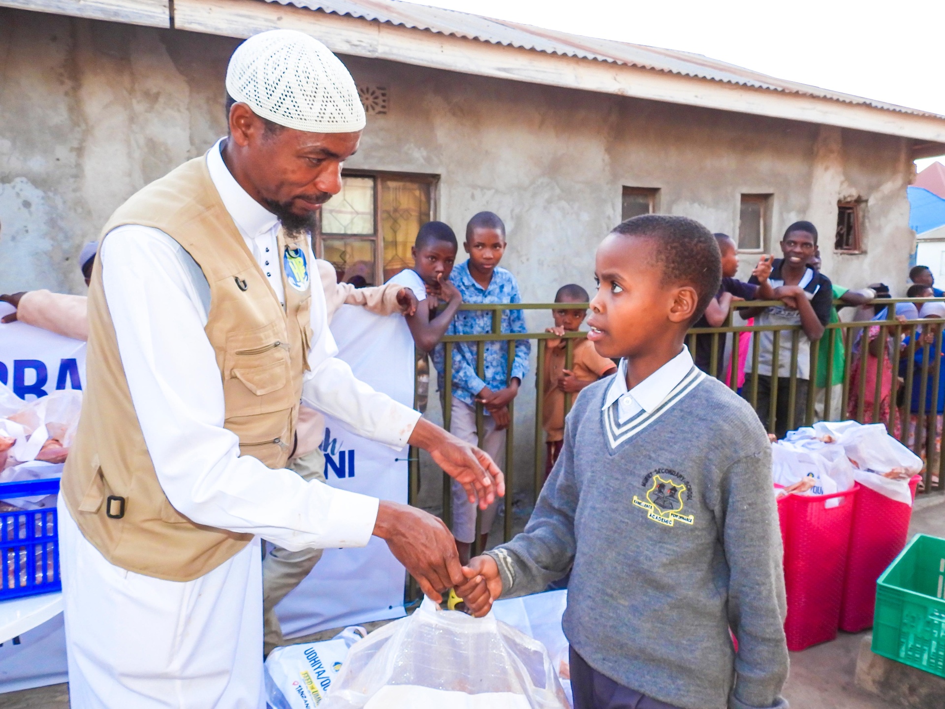 Br. Sharani, an HDF Field Coordinator, handing a Qurbani meat share to a young girl during the Tanzania distribution.